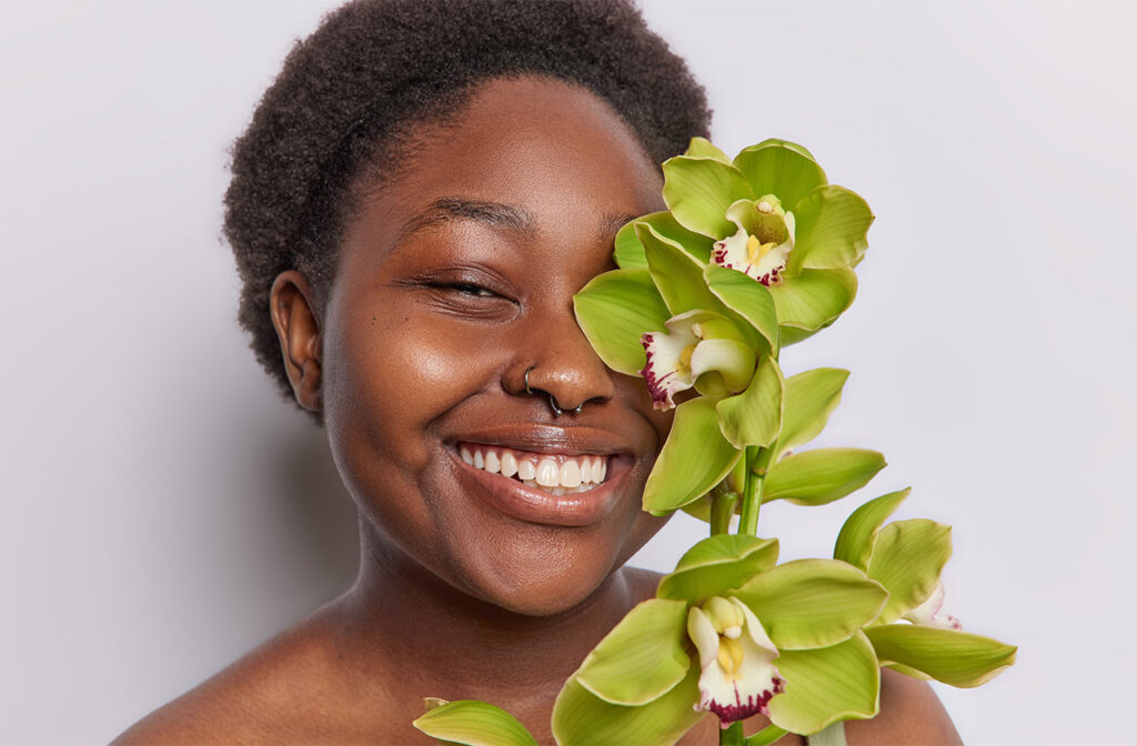 Beautiful black girl with nose piercings behind orchid flower